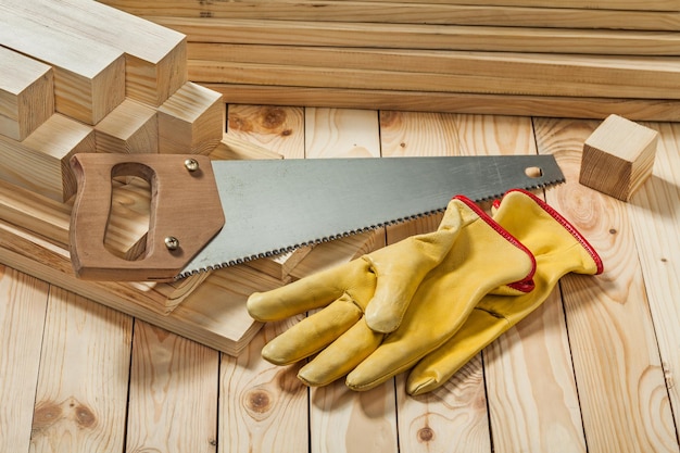 Serrucho y guantes de trabajo amarillos en materiales de madera