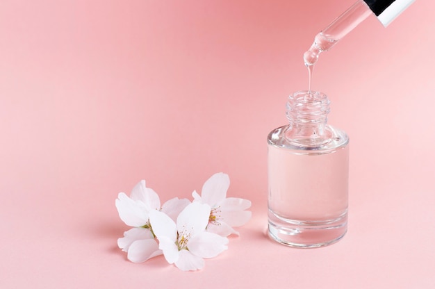 Serum und Tropfer auf einer rosa Hintergrundnahaufnahme, Naturkosmetikkonzept