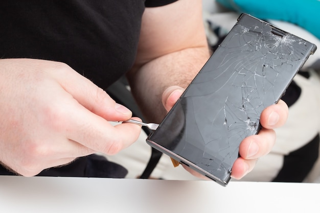 Foto service-center für die reparatur von mobiltelefonen. der assistent entfernt das bildschirmschutzglas von einem smartphone