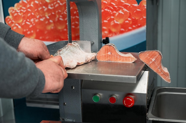 Service zum Schneiden von gefrorenem Lachsfisch auf einem Steak in einem Fischsupermarkt mit professioneller Ausrüstung