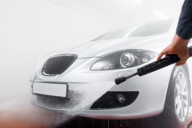 Serviceman Hand mit Schlauch im Autowaschservice