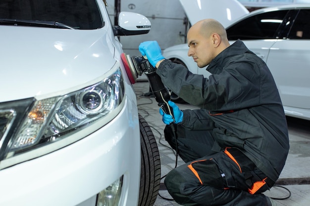 Serviceman Polieren Autokarosserie mit Maschine in einer Werkstatt.