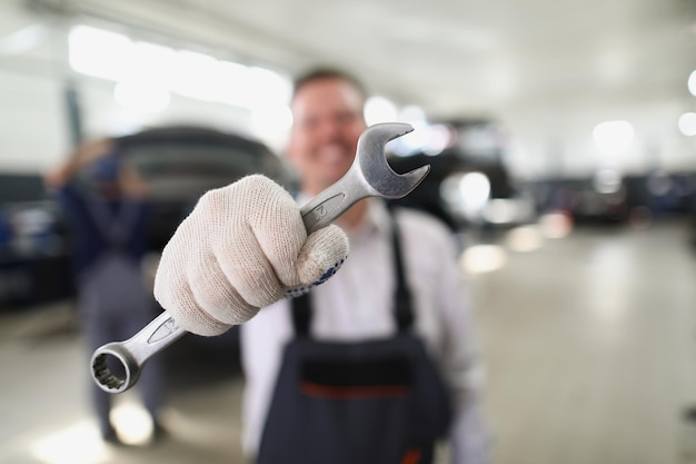 Servicemitarbeiter halten Metallwerkzeug für Schraubenschlüssel, um das Fahrzeug zu reparieren