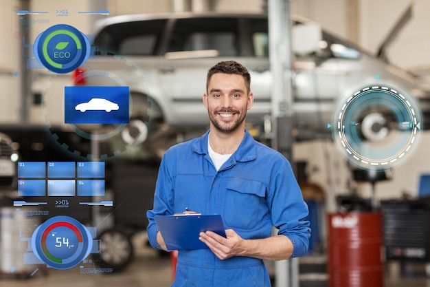 servicio de automóviles, reparación, mantenimiento y concepto de personas - un feliz y sonriente mecánico de automóviles o un herrero con un clipboard en el taller