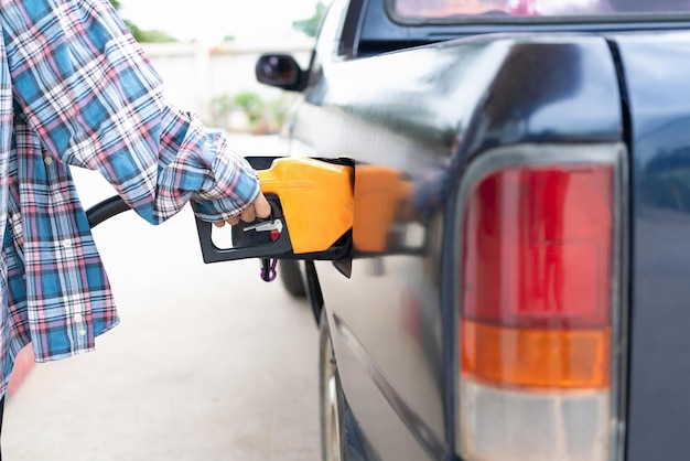 El servicio comercial de llenado de petróleo transfiere gas de la gasolinera al automóvil negro