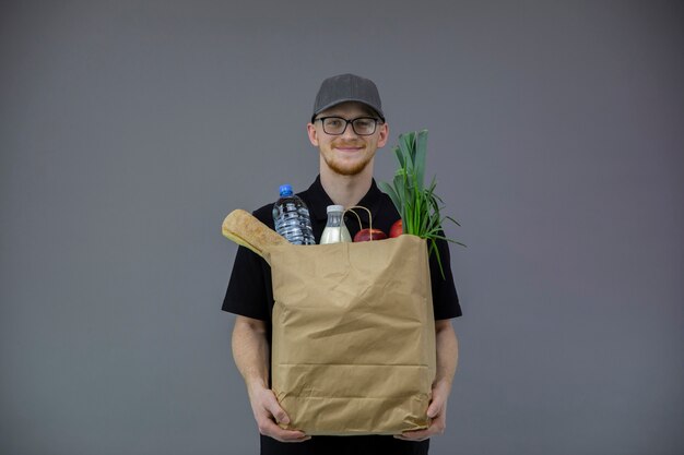 Servicio de entrega de alimentos hombre con caja de comestibles sobre fondo gris con espacio de copia