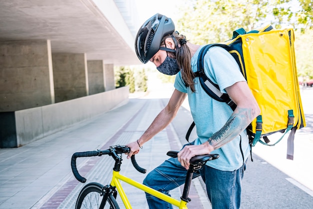 Foto servicio de entrega de alimentos por servicio de entrega. ciclista con máscara por seguridad.