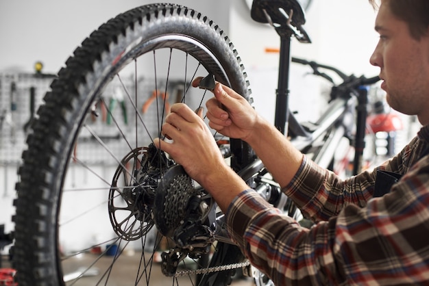 Servicio de fabricación de mecánico masculino en el taller de reparación de bicicletas con herramientas