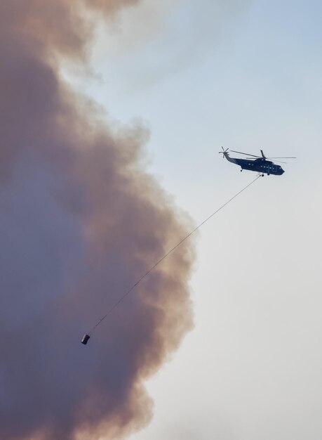 Servicio de incendios forestales Helicóptero sobrevolando BC Forest Fire y Smoke en la montaña cerca de Hope