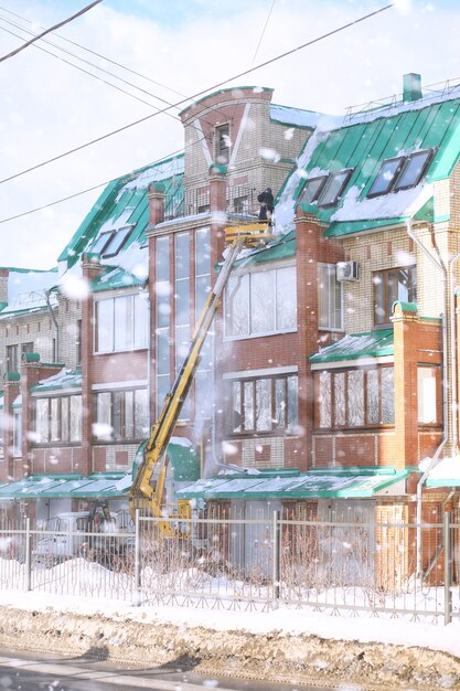 El servicio de limpieza limpia la nieve del techo de la casa. Los trabajadores de equipos especiales limpian la nieve en invierno. Limpiar el hielo y la nieve de los tejados de las casas.