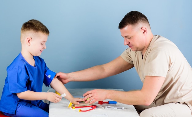 Servicio médico Hombre médico sentarse mesa herramientas médicas examinar niño pequeño paciente Cuidado de la salud Concepto de pediatra Pediatra cuidadoso verificar la salud del niño Examen médico Trabajador del hospital