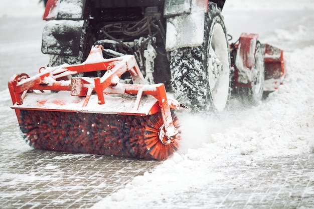 Servicio municipal de limpieza de nieve, un pequeño tractor con un cepillo giratorio despeja un camino en el parque de la ciudad