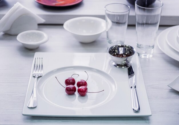 Servicio de plato de cerámica con cerezas en mesa de madera