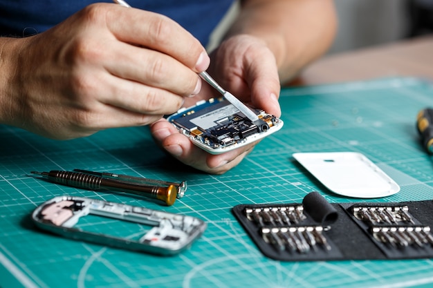 Foto servicio de reparación de electrónica. técnico desmontando smartphone para inspeccionar.
