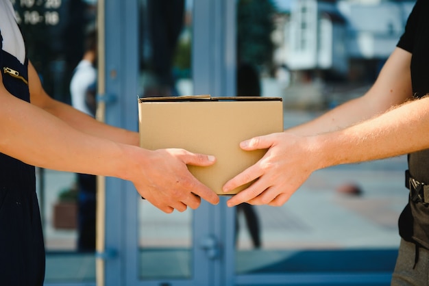 Servicio de repartidor con cajas en las manos de pie delante de las puertas de la casa del cliente