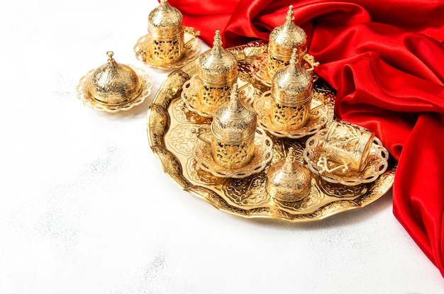 Servicio de té árabe con tazas doradas y decoración en rojo. Concepto de hospitalidad