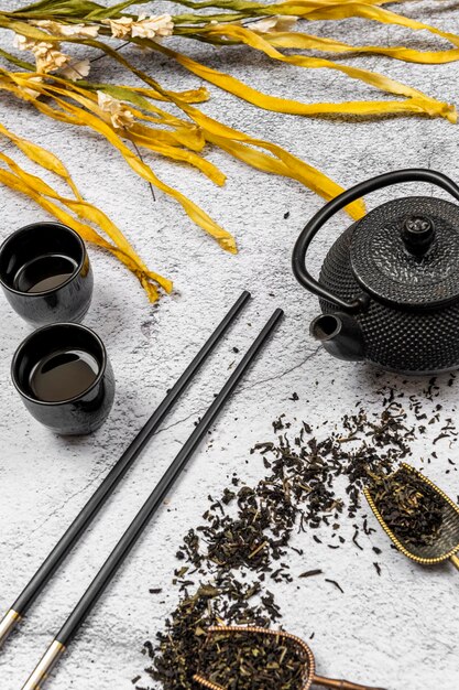 Servicio de té japonés con flores y palillos de té seco y tacitas