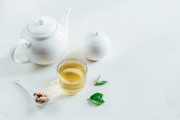 Servicio de té con té en una taza transparente sobre blanco