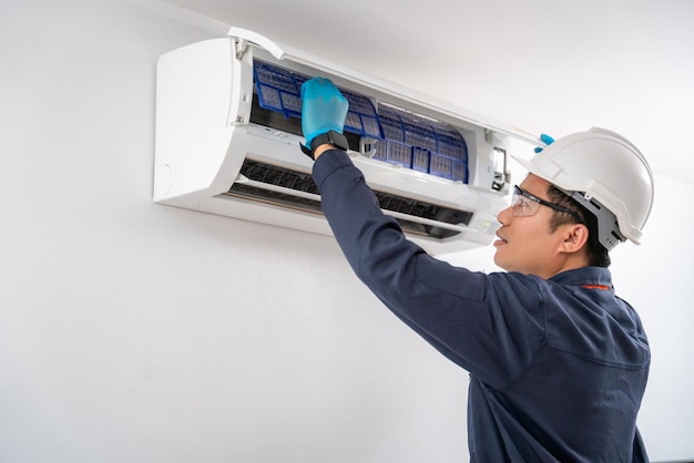 Servicio técnico de aire quitando el filtro de aire del acondicionador de aire para limpiarlo en la pared blanca Concepto de servicio de un técnico de aire acondicionado