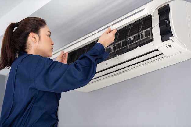 El servicio técnico femenino abre el aire acondicionado interior para revisarlo y repararlo