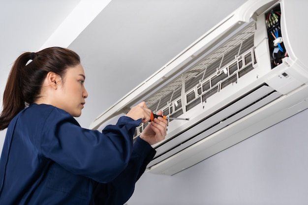 Foto servicio técnico femenino con destornillador para reparar el aire acondicionado en interiores