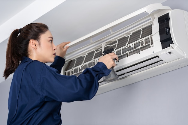 Servicio técnico femenino limpiando el aire acondicionado en interiores