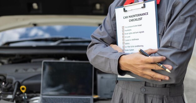 Servicios de máquinas de motor de automóviles Mecánico de automóviles reparador comprobando un motor de automóvil con inspección escribiendo en el portapapeles la lista de comprobación para el servicio y mantenimiento de máquinas de reparación de automóviles
