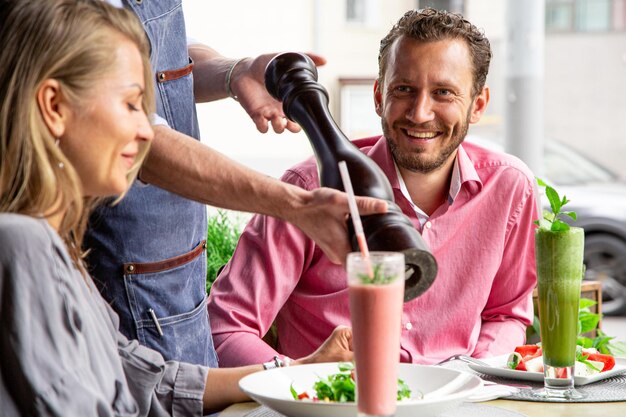 Serviço ao cliente de restaurantes conceito O garçom enche a salada com pimenta fresca