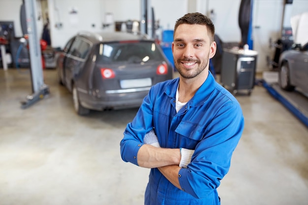 serviço de carro, reparo, manutenção e conceito de pessoas - homem mecânico de automóveis sorridente feliz ou ferreiro na oficina