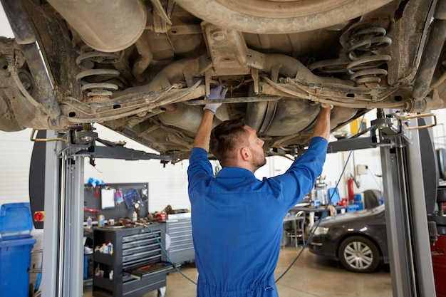 serviço de carro, reparo, manutenção e conceito de pessoas - mecânico de automóveis ou ferreiro trabalhando na oficina