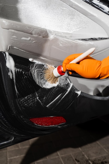 Serviço de detalhamento do carro Trabalhador no serviço de limpeza que lava o interior do carro do cliente Processo de limpeza com espuma e detergente com escova painel de cartão da porta do carro