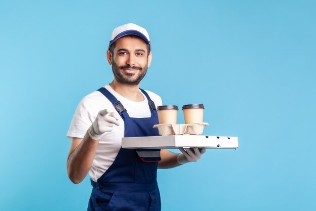 Serviço de entrega correio feliz sorridente de macacão segurando a caixa de pizza de café usando luvas de segurança e oferecendo bebidas comida apontando o dedo para a câmera escolhendo você tiro de estúdio interno isolado