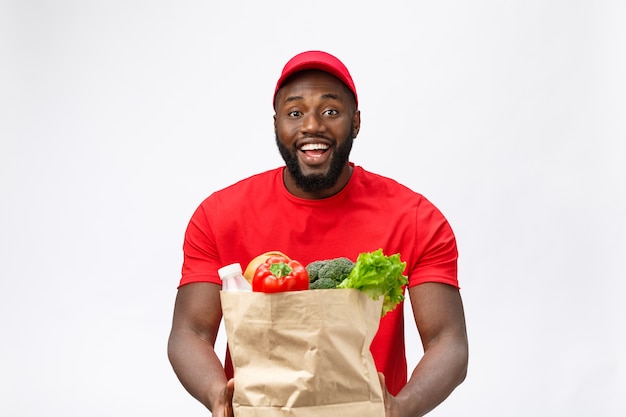 Serviço de entrega - homem afro-americano bonito entregador carregando pacote de comida e bebida da loja.