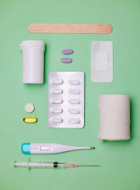 Serviços de saúde fornecem ferramentas médicas e comprimidos para bem-estar e kit de primeiros socorros com bandagem de cima no estúdio Termômetro equipamento médico e injeção para remédio líquido por fundo verde