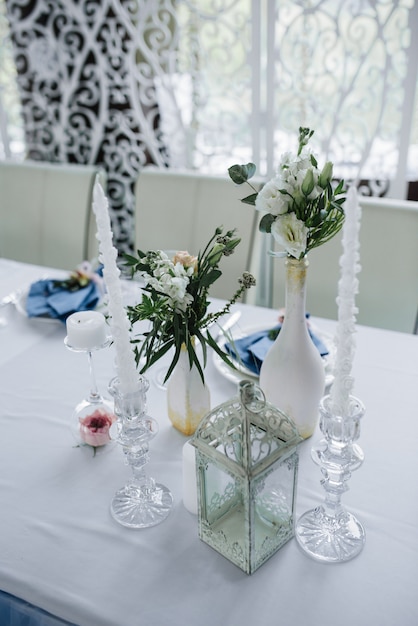 Servido para la mesa del banquete de boda en azul blanco. Decoración de boda. Servilleta azul con flores en un plato blanco. Arco calado.