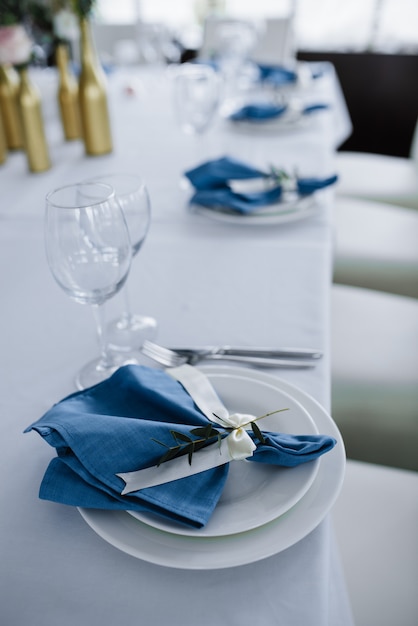 Servido para la mesa del banquete de boda en azul blanco. Decoración de boda. Servilleta azul con flores en un plato blanco.