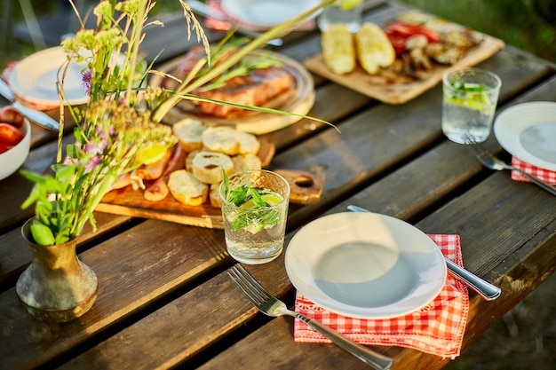 Servido con platos en la mesa de la cena picnic de verano al aire libre en el patio trasero de la casa al aire libre