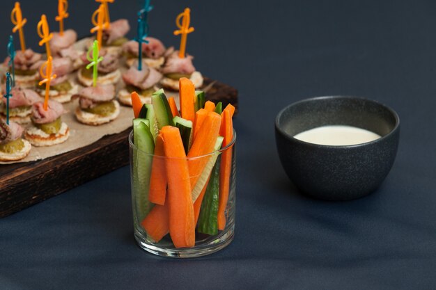 Servieren von frischem Gemüse in einzelnen Glasbehältern mit Karotten- und Gurkenscheiben mit Käsesauce.