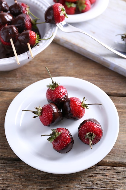 Servierter Tisch mit köstlichen Erdbeeren in Schokolade auf Holzhintergrund