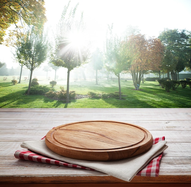 Serviette und Brett für Pizza auf Holzschreibtisch. Sommerlandschaft.