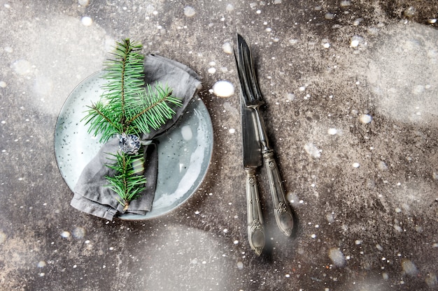 servilleta con anillo y rama de árbol de Navidad, mesa puesta en tono plateado