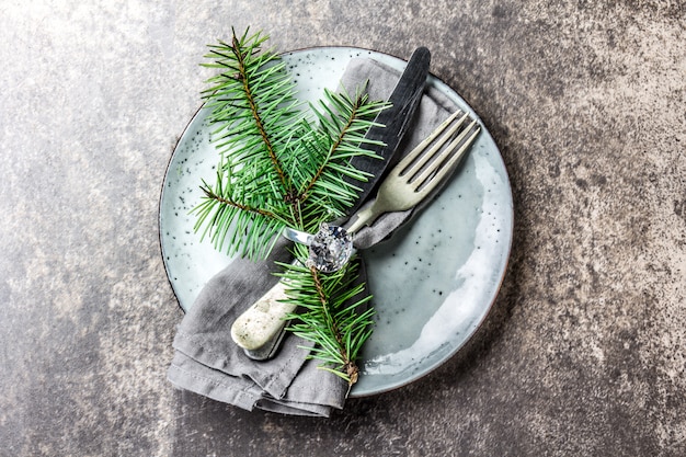 servilleta con anillo y rama de árbol de Navidad, mesa puesta en tono plateado