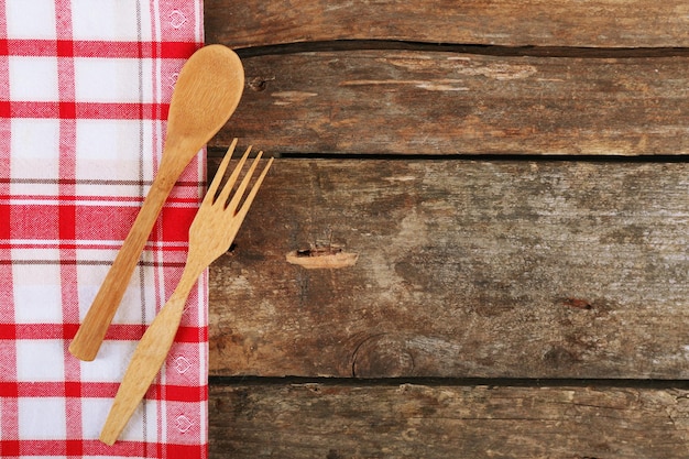 Servilleta a cuadros con tenedor y cuchara sobre fondo de mesa de madera
