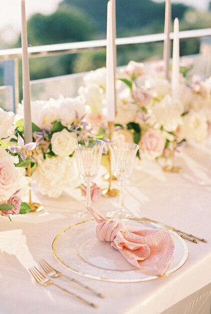 Foto una servilleta rosa anudada en un plato en una mesa festiva cerca de un ramo de flores