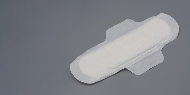 Servilleta sanitaria. Servilletero sanitario suave y confortable y fondo gris. Sábana encimera blanca. Tiro del estudio aislado. Almohadillas de tela para la menstruación. Tipo de ala para la noche. Absorbente rápido. Sensación suave de algodón.