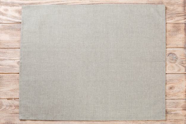 Servilleta de tela gris sobre madera rústica marrón, vista superior con espacio de copia