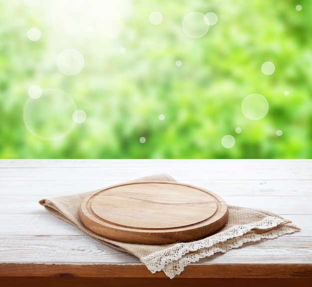 Servilleta de tela vacía con encaje, mantel en perspectiva de mesa de madera. Paisaje de verano.