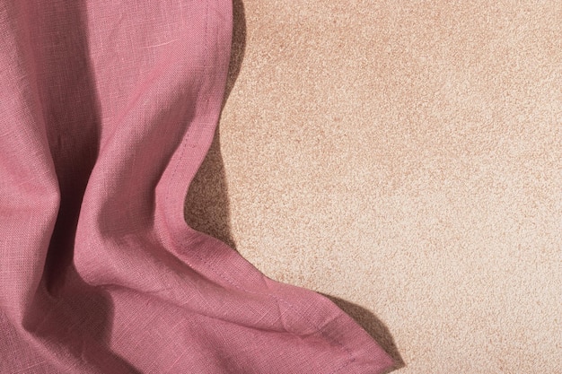 Servilleta textil rosa sobre fondo enlucido beige