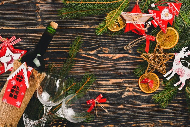 Servindo a mesa de natal e uma garrafa de vinho árvore de natal de ano novo e enfeites de árvore de natal em um fundo de madeira espaço livre para texto