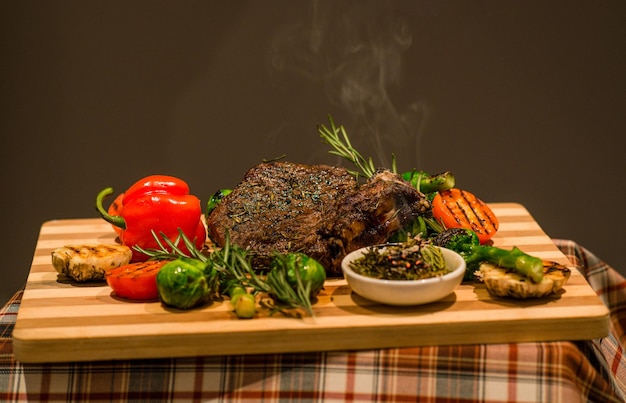 Servindo a mesa para o almoço carne frita legumes pimentão e batatas grelhadas na placa de madeira